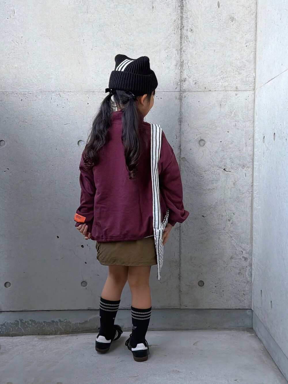 ブラック系のスニーカー、グリーン系のスカート、レッド系のスウェットを着用したキッズの秋コーディネートの3枚目の写真