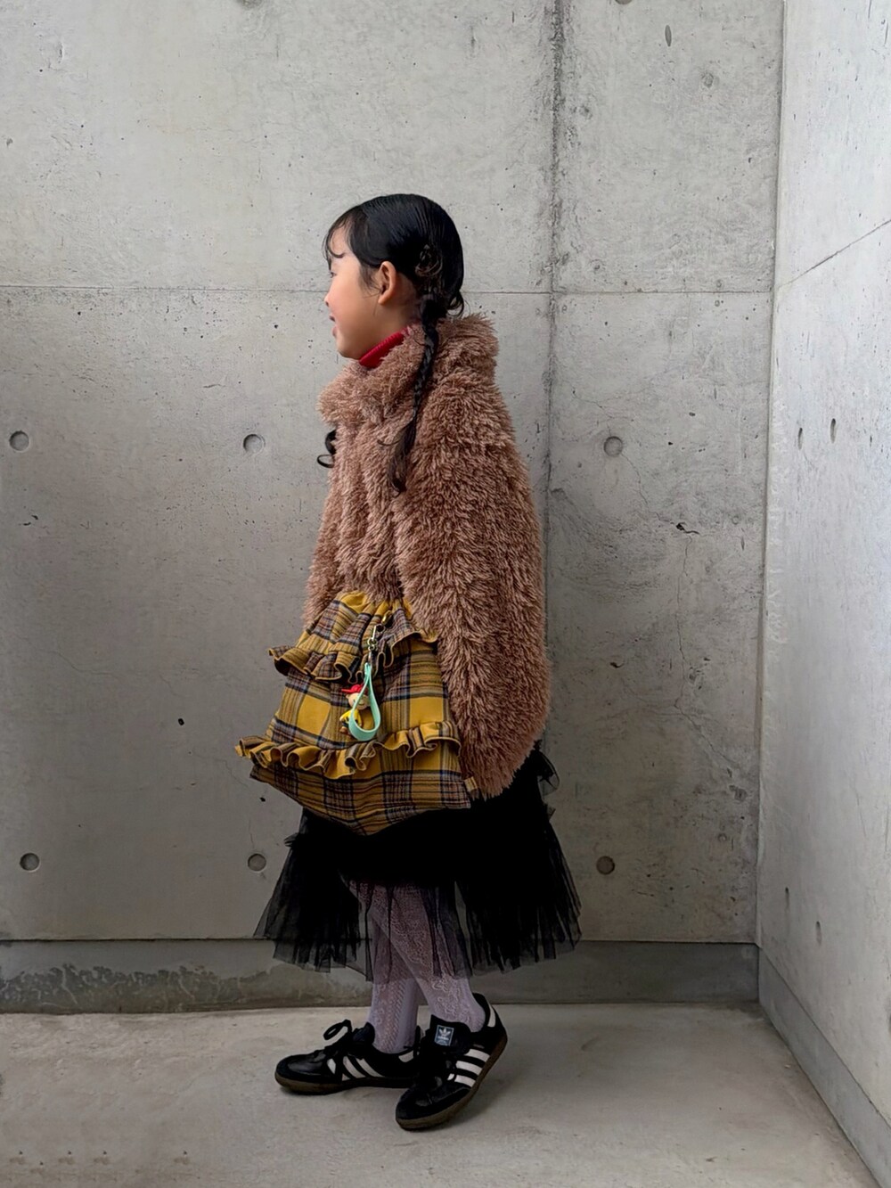 イエロー系のバックパック/リュック、ブラック系のスニーカー、レッド系のニット/セーターを着用したキッズの冬コーディネートの2枚目の写真