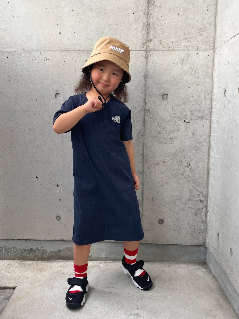 ブラック系のサンダル、ブルー系のワンピース、ベージュ系のハットを着用したキッズの夏コーディネートの2枚目の写真