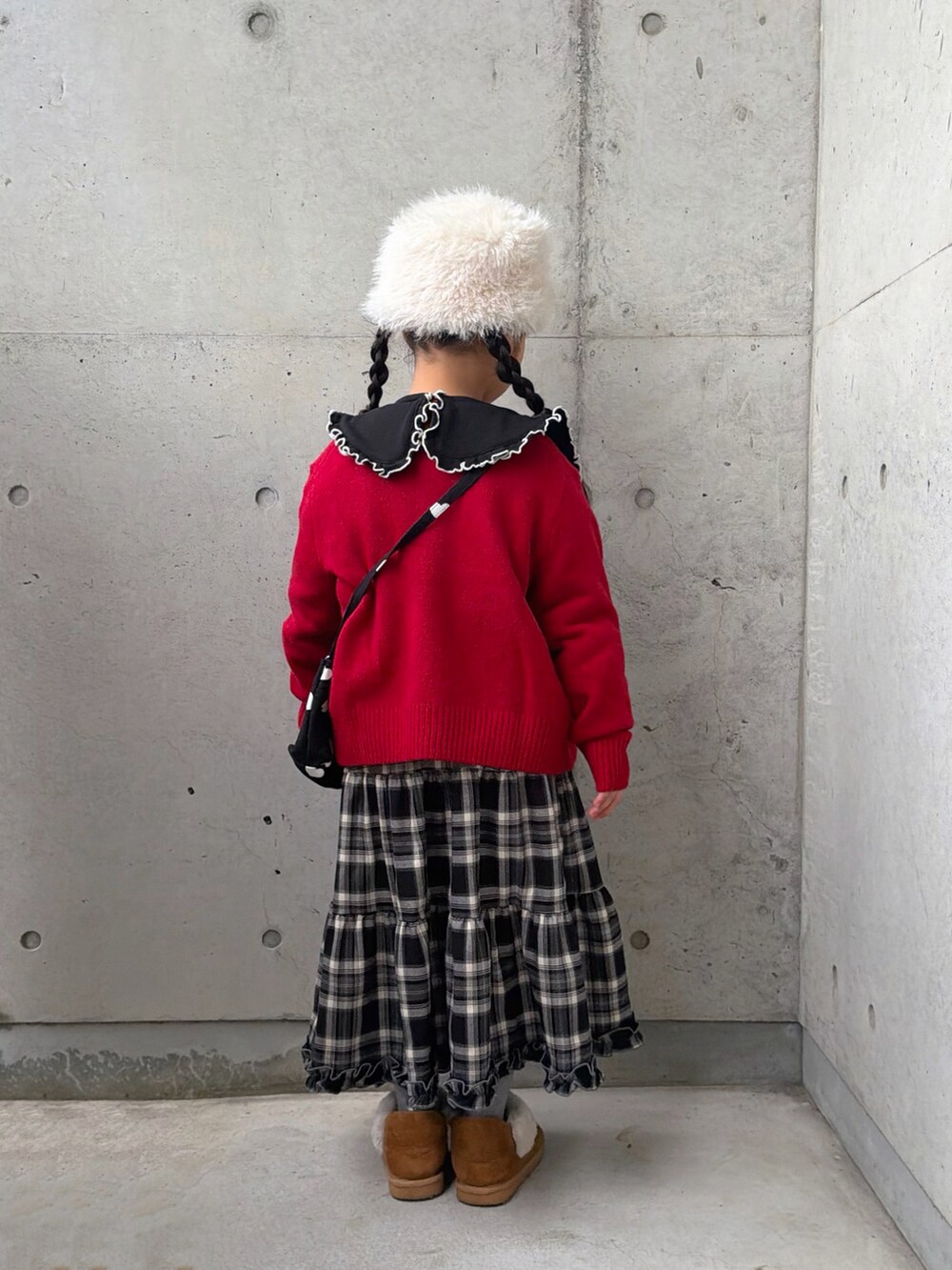 ブラック系のスウェット、ブラウン系のスカート、ブラック系のショルダーバッグを着用したキッズの冬コーディネートの3枚目の写真