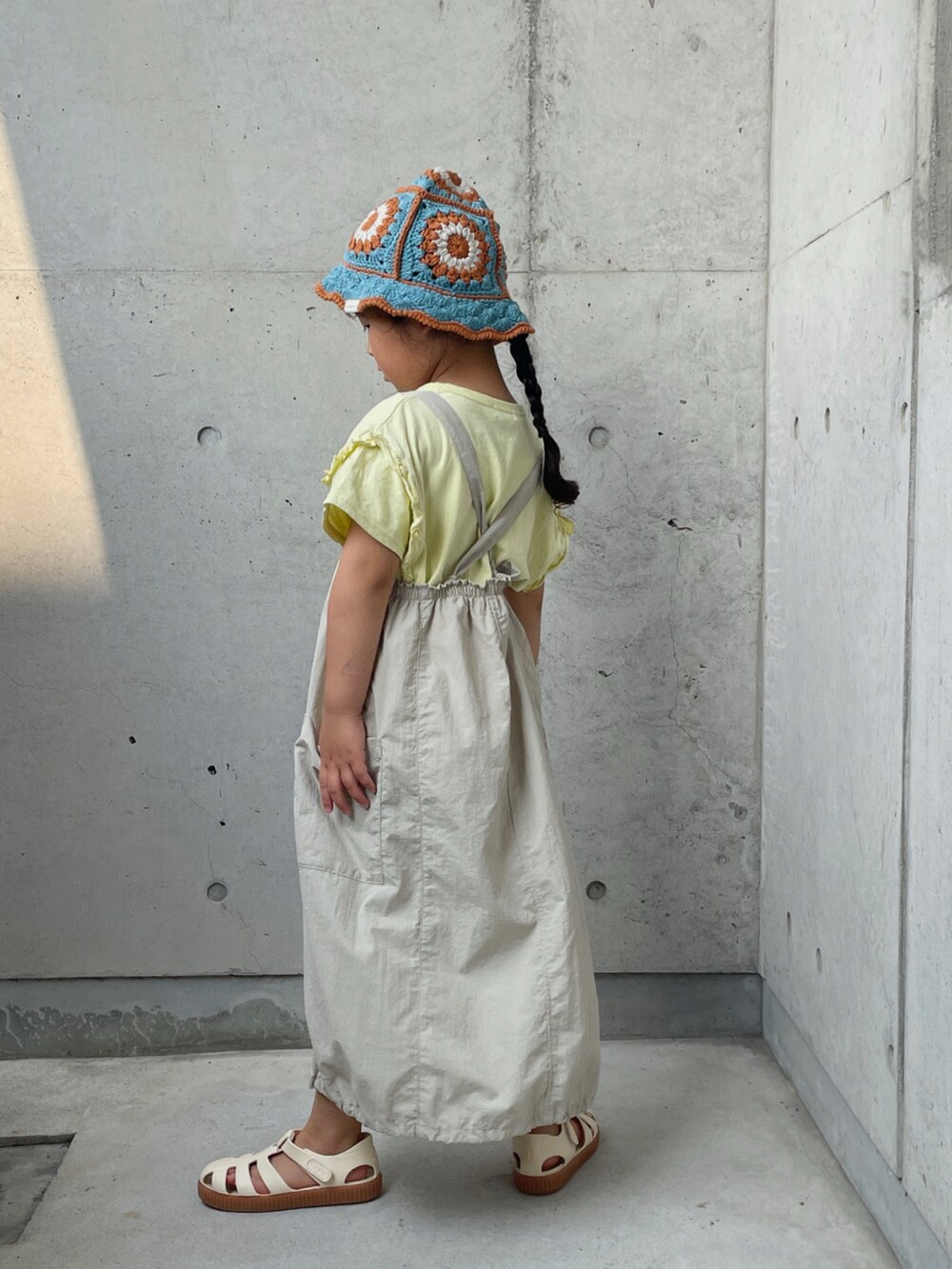 ベージュ系のTシャツ/カットソー、ベージュ系のワンピース、ホワイト系のサンダルを着用したキッズの夏コーディネートの2枚目の写真