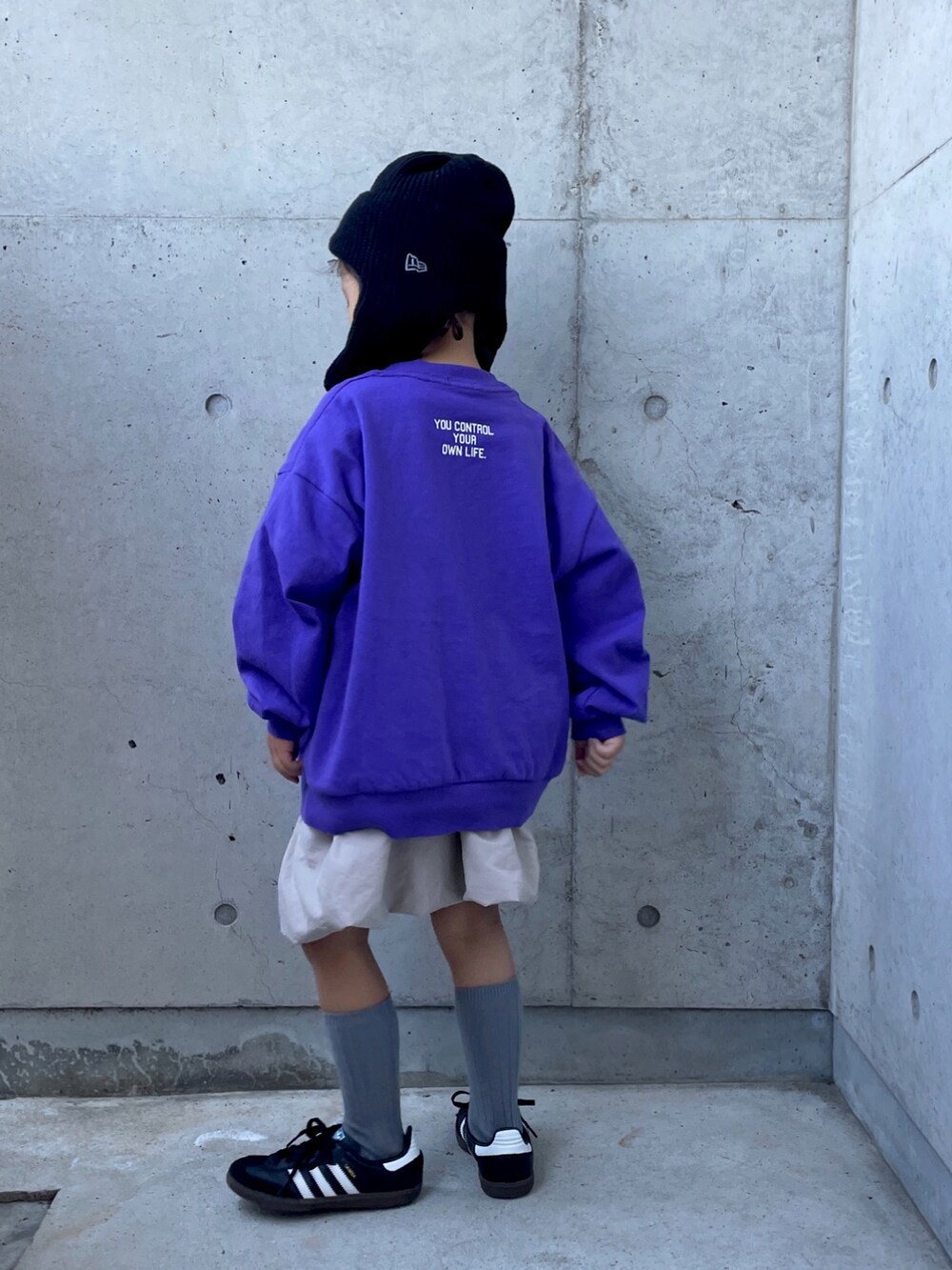 ベージュ系のスカート、パープル系のTシャツ/カットソー、ブラック系のスニーカーを着用したキッズの秋コーディネートの2枚目の写真