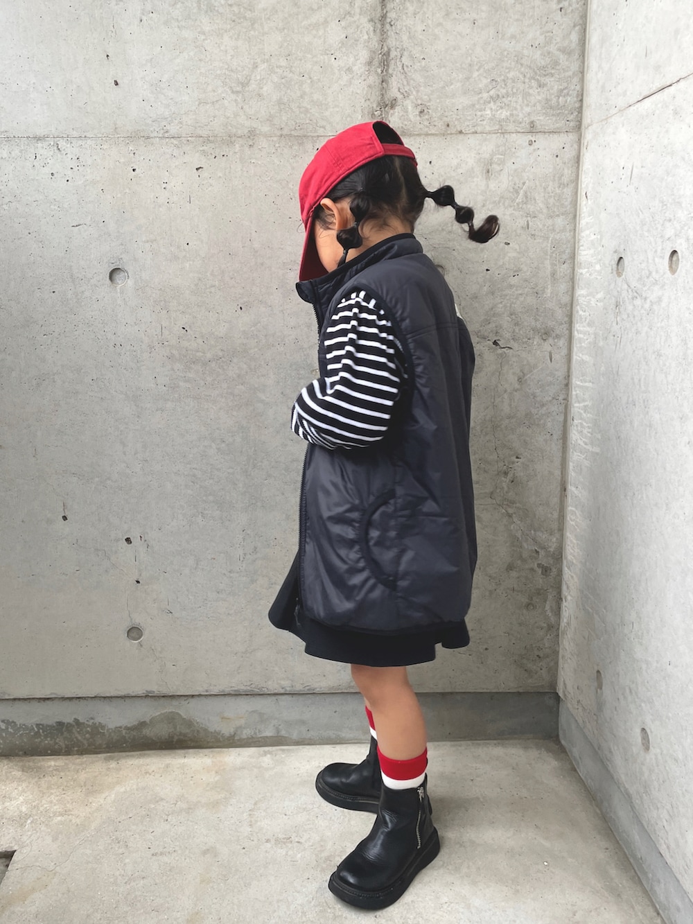 ブラック系のベスト、グレー系のワンピース、ブラック系のブーツを着用したキッズの春コーディネートの2枚目の写真