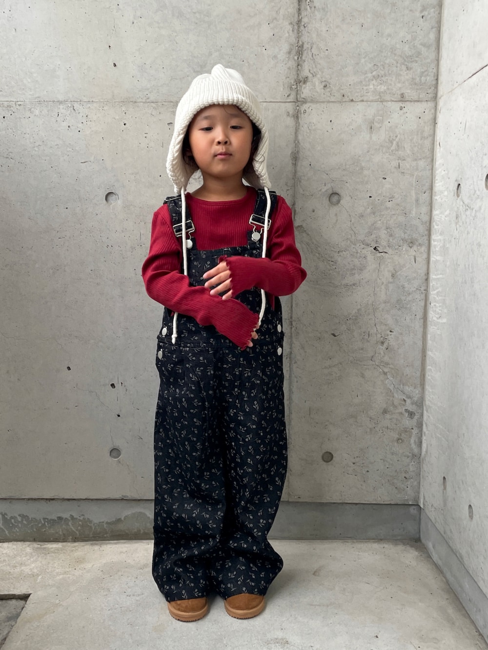 ブラウン系のブーツ、ブラック系のオールインワン・サロペット、ホワイト系のTシャツ/カットソーを着用したキッズの秋コーディネートの2枚目の写真