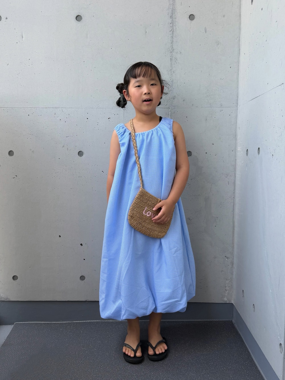 ブルー系のワンピース、ベージュ系のショルダーバッグ、ブラック系のサンダルを着用したキッズの夏コーディネートの5枚目の写真