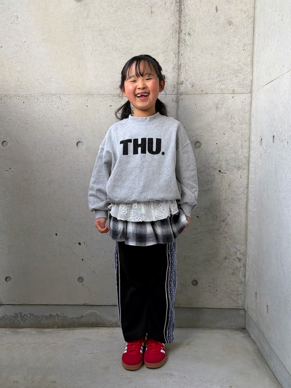 グレー系のスウェット、ブラック系のスカート、レッド系のスニーカーを着用したキッズの冬コーディネートの5枚目の写真