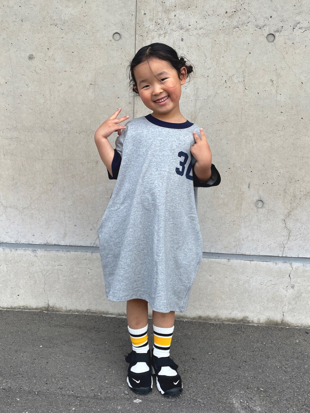 グレー系のワンピース、ブラック系のスニーカー、ブラック系のソックス/靴下を着用したキッズの春コーディネートの2枚目の写真