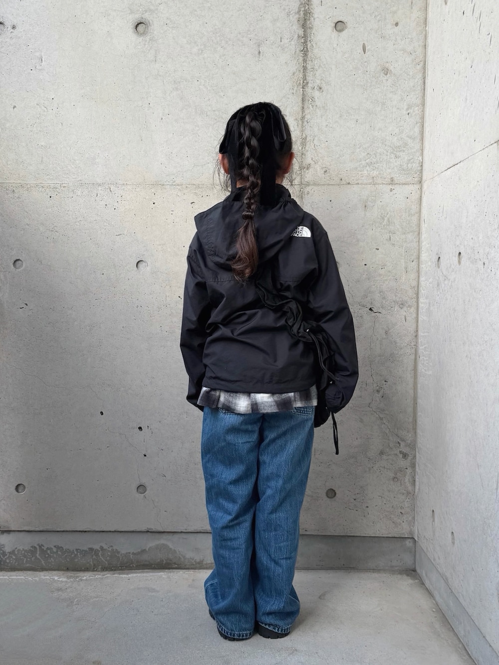 ブラック系のスカート、グレー系のブーツ、ブラック系のマウンテンパーカーを着用したキッズの春コーディネートの3枚目の写真