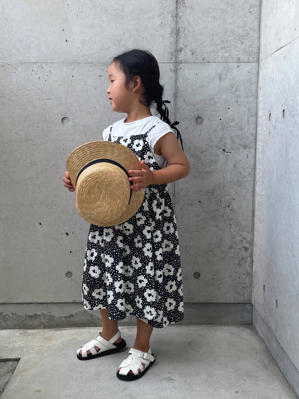 ブラック系のワンピース、ホワイト系のサンダル、ベージュ系のハットを着用したキッズの夏コーディネートの3枚目の写真