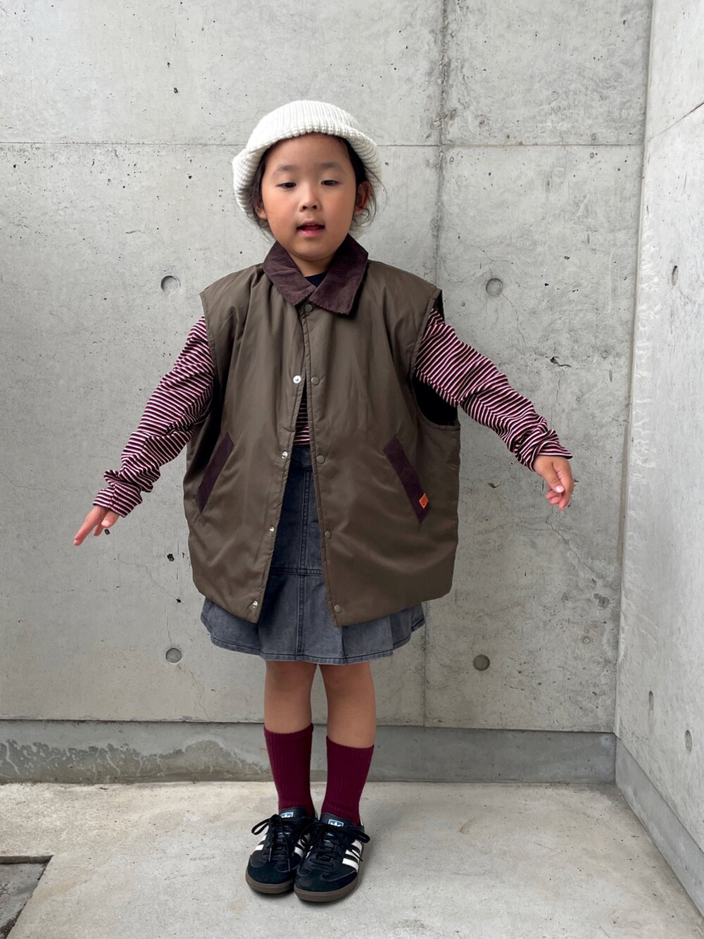 レッド系のTシャツ/カットソー、グリーン系のブルゾン、グレー系のスカートを着用したキッズの秋コーディネートの2枚目の写真