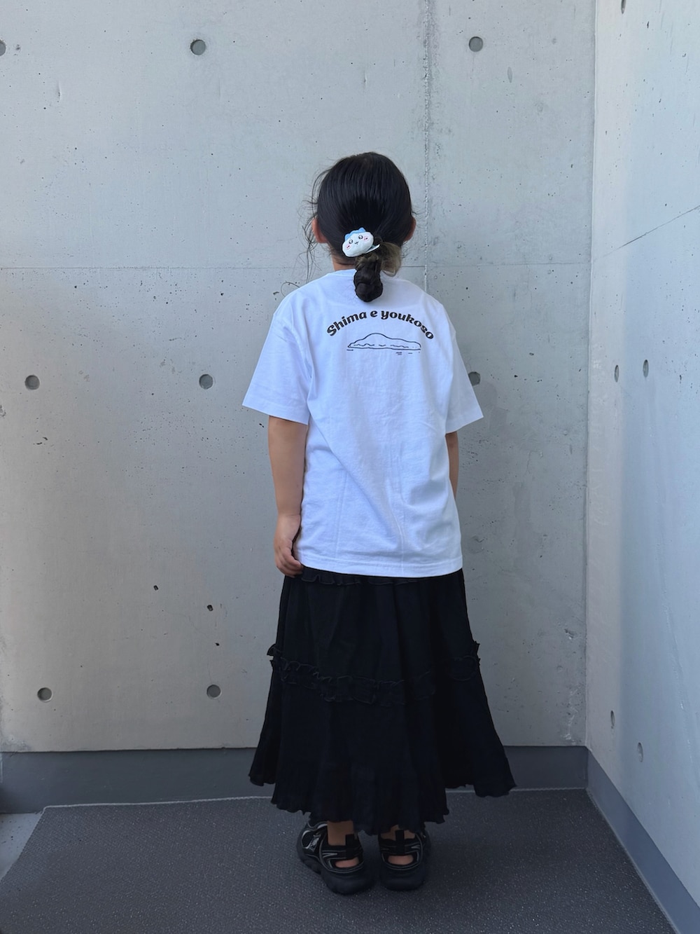 ブラック系のサンダル、ブラック系のスカート、ホワイト系のTシャツ/カットソーを着用したキッズの夏コーディネートの4枚目の写真