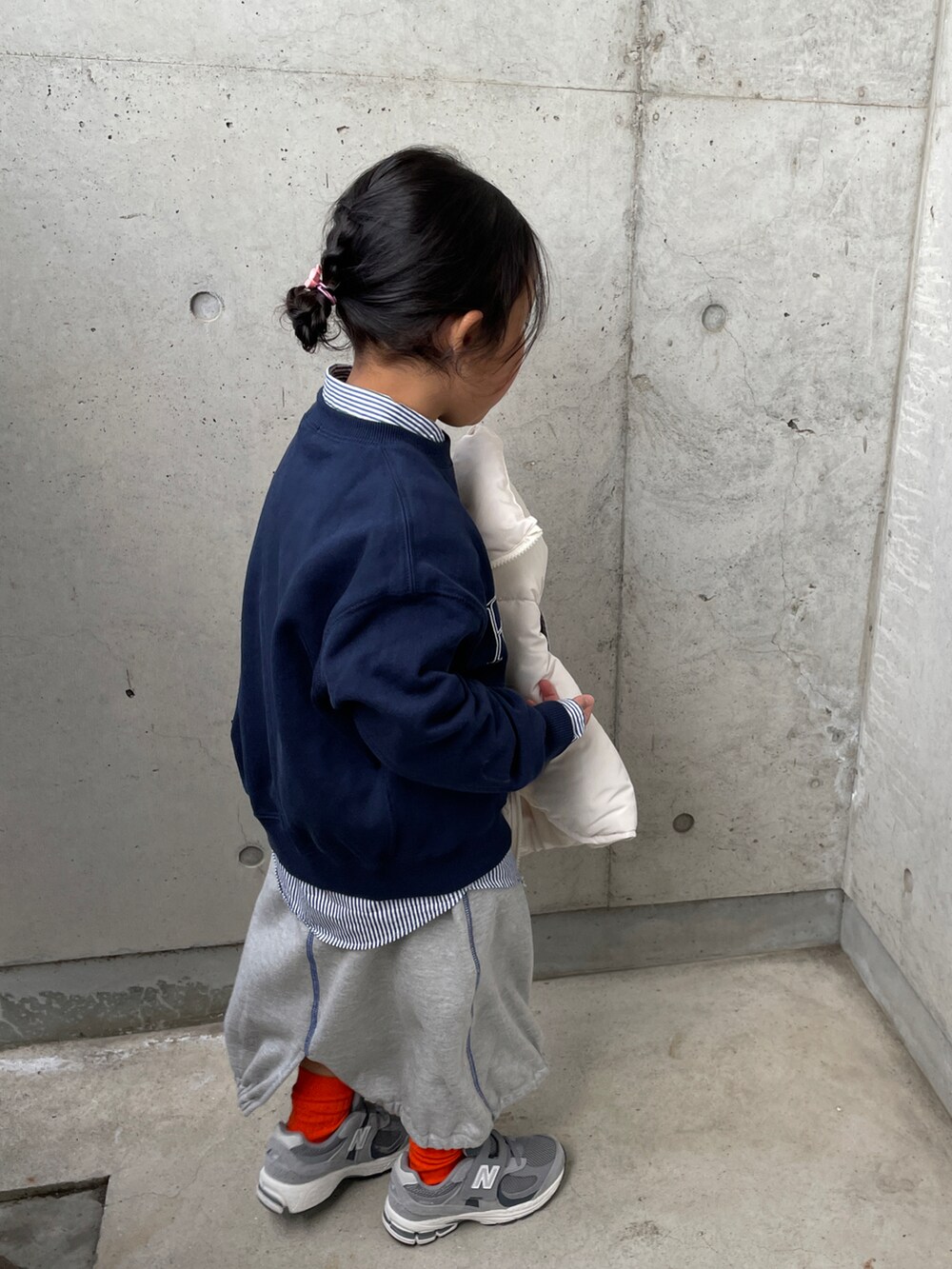 ホワイト系のダウンベスト、ブルー系のスウェット、グレー系のスカートを着用したキッズの春コーディネートの3枚目の写真