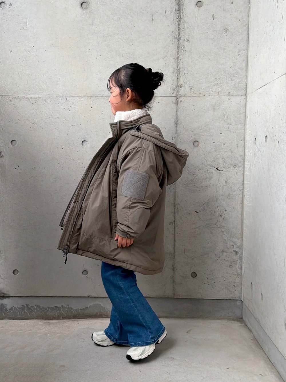 グリーン系のブルゾン、ブルー系のデニムパンツ、ホワイト系のトップスを着用したキッズの秋コーディネートの2枚目の写真