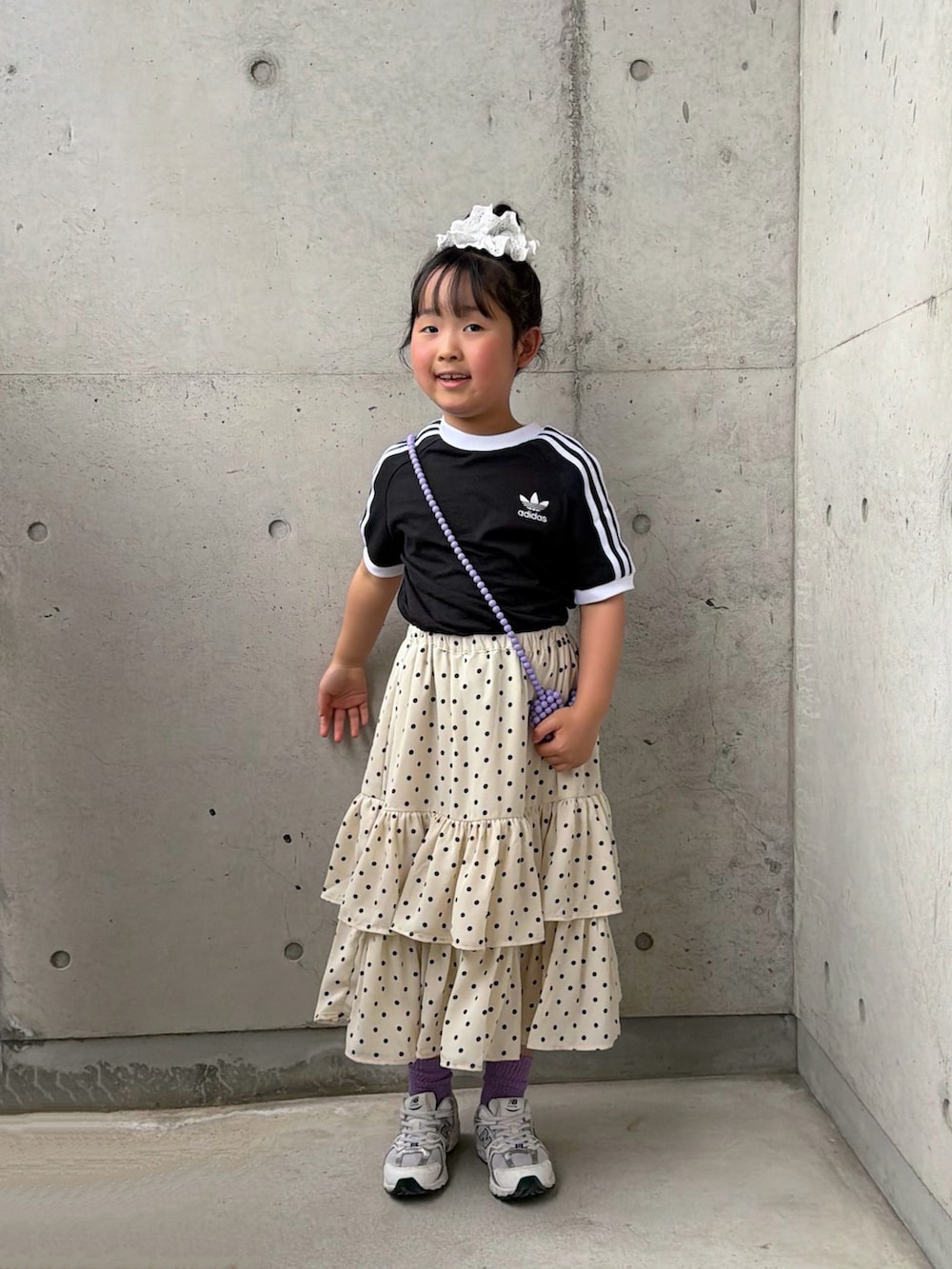 ホワイト系のスカート、ホワイト系のスニーカー、ブラック系のTシャツ/カットソーを着用したキッズの春コーディネートの3枚目の写真