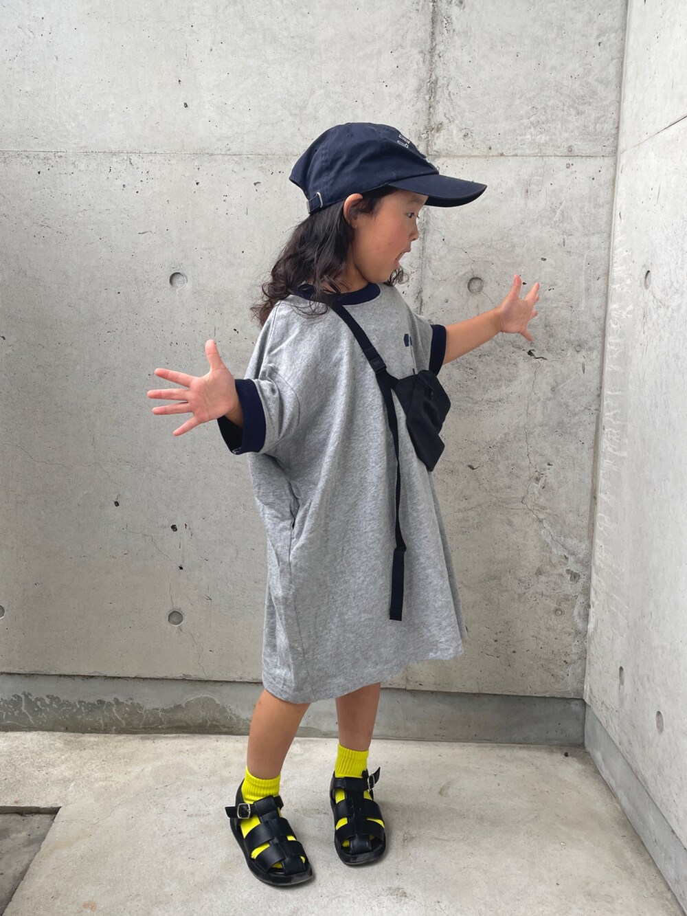 グレー系のワンピース、ブラック系のサンダル、ブルー系のキャップを着用したキッズの夏コーディネートの4枚目の写真