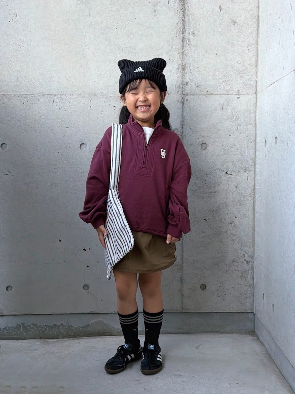 ブラック系のスニーカー、グリーン系のスカート、レッド系のスウェットを着用したキッズの秋コーディネートの4枚目の写真