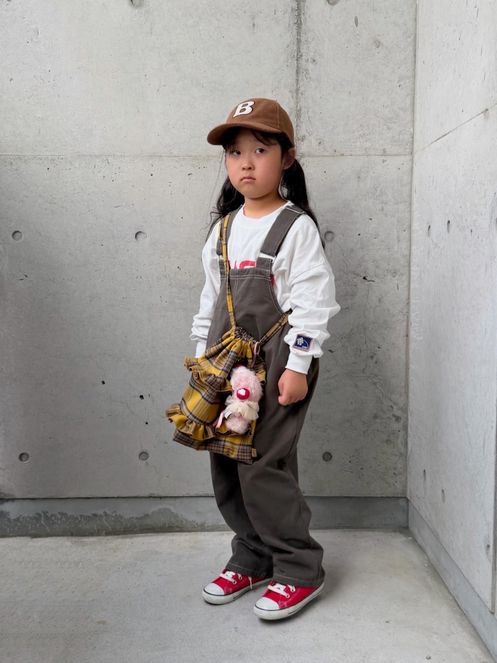 レッド系のスニーカー、グレー系のサロペット/オーバーオール、イエロー系のバックパック/リュックを着用したキッズの秋コーディネートの2枚目の写真