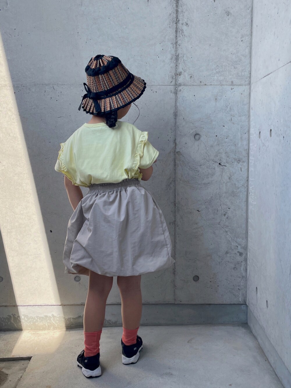 ブラック系のスニーカー、ベージュ系のTシャツ/カットソー、ベージュ系のスカートを着用したキッズの夏コーディネートの3枚目の写真