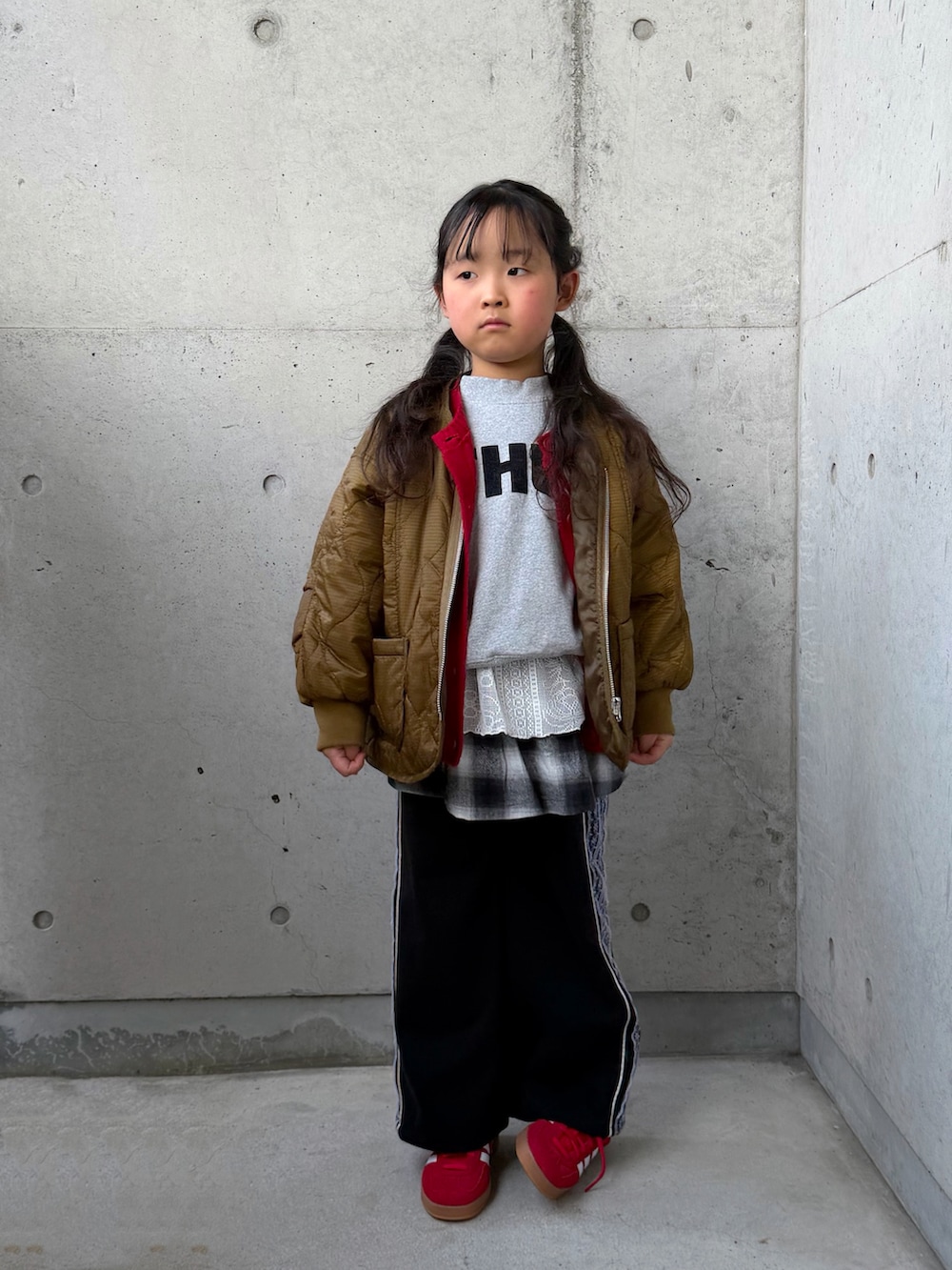 グレー系のスウェット、ブラック系のスカート、レッド系のスニーカーを着用したキッズの冬コーディネートの2枚目の写真