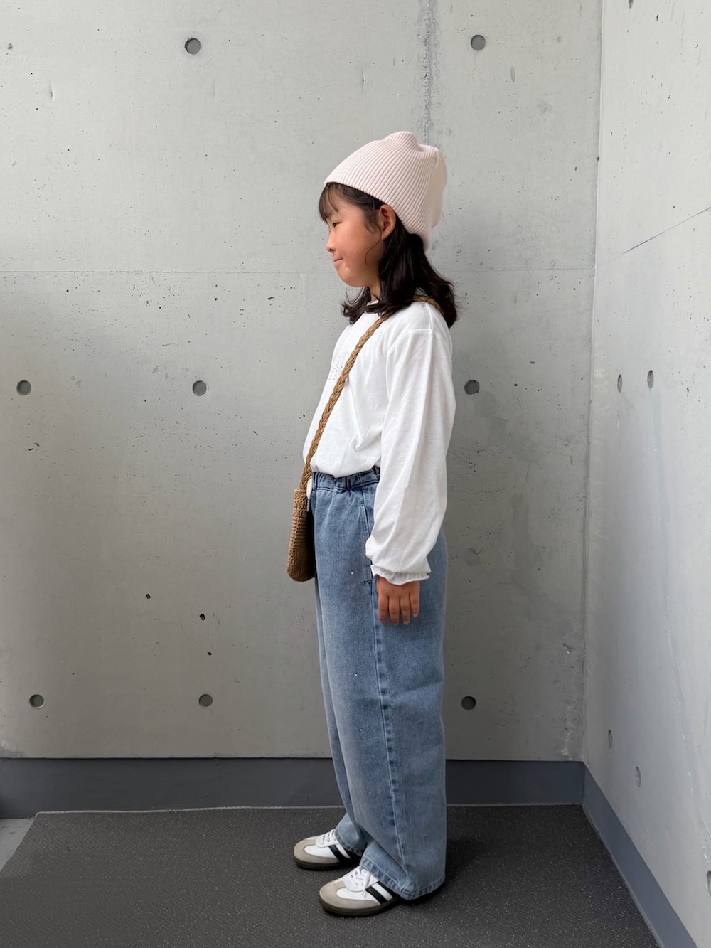 ベージュ系のショルダーバッグ、ホワイト系のTシャツ/カットソー、ブルー系のデニムパンツを着用したキッズの秋コーディネートの2枚目の写真