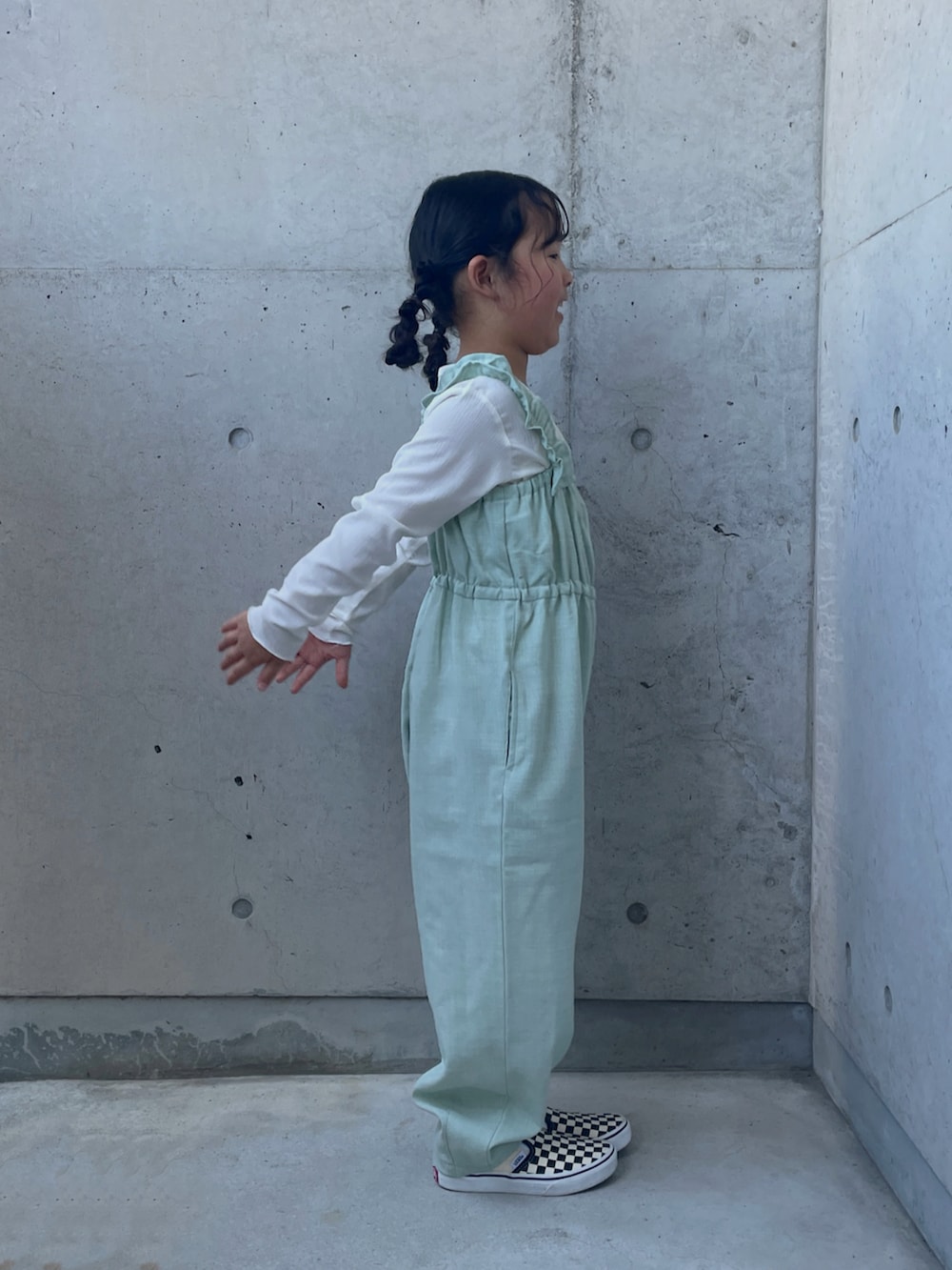 グリーン系のつなぎ/オールインワン、ブラック系のスリッポン、ブラック系のワンピース/ドレスを着用したキッズの秋コーディネートの2枚目の写真