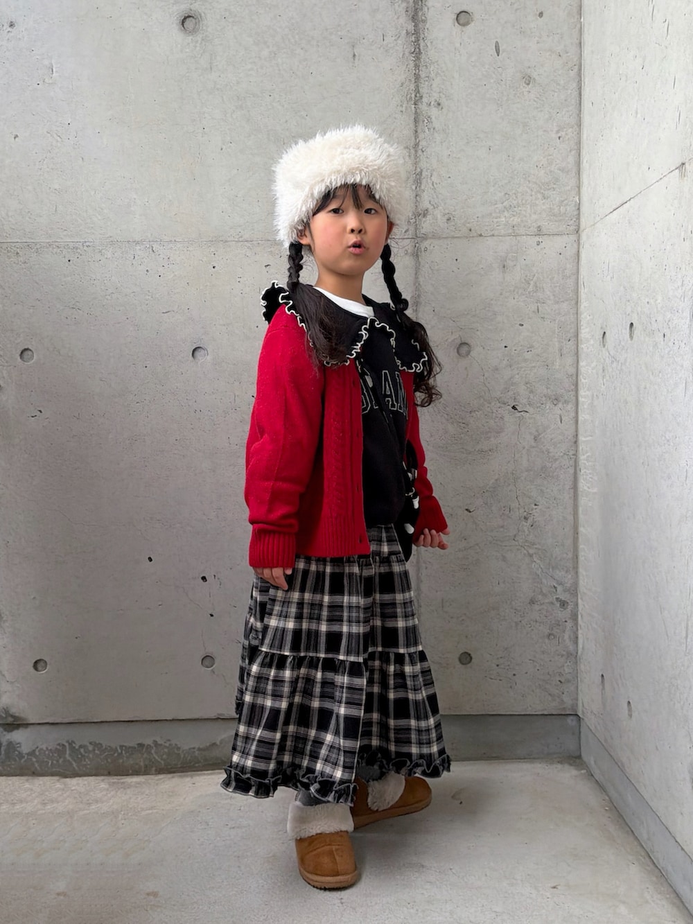 ブラック系のスウェット、ブラウン系のスカート、ブラック系のショルダーバッグを着用したキッズの冬コーディネートの2枚目の写真