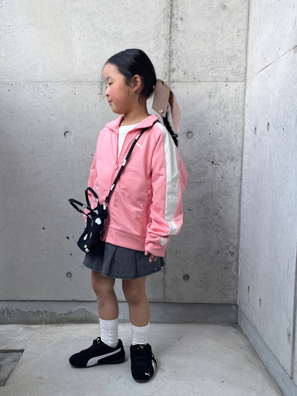 ピンク系のジャージ、グレー系のスカート、ブラック系のスニーカーを着用したキッズの春コーディネートの3枚目の写真