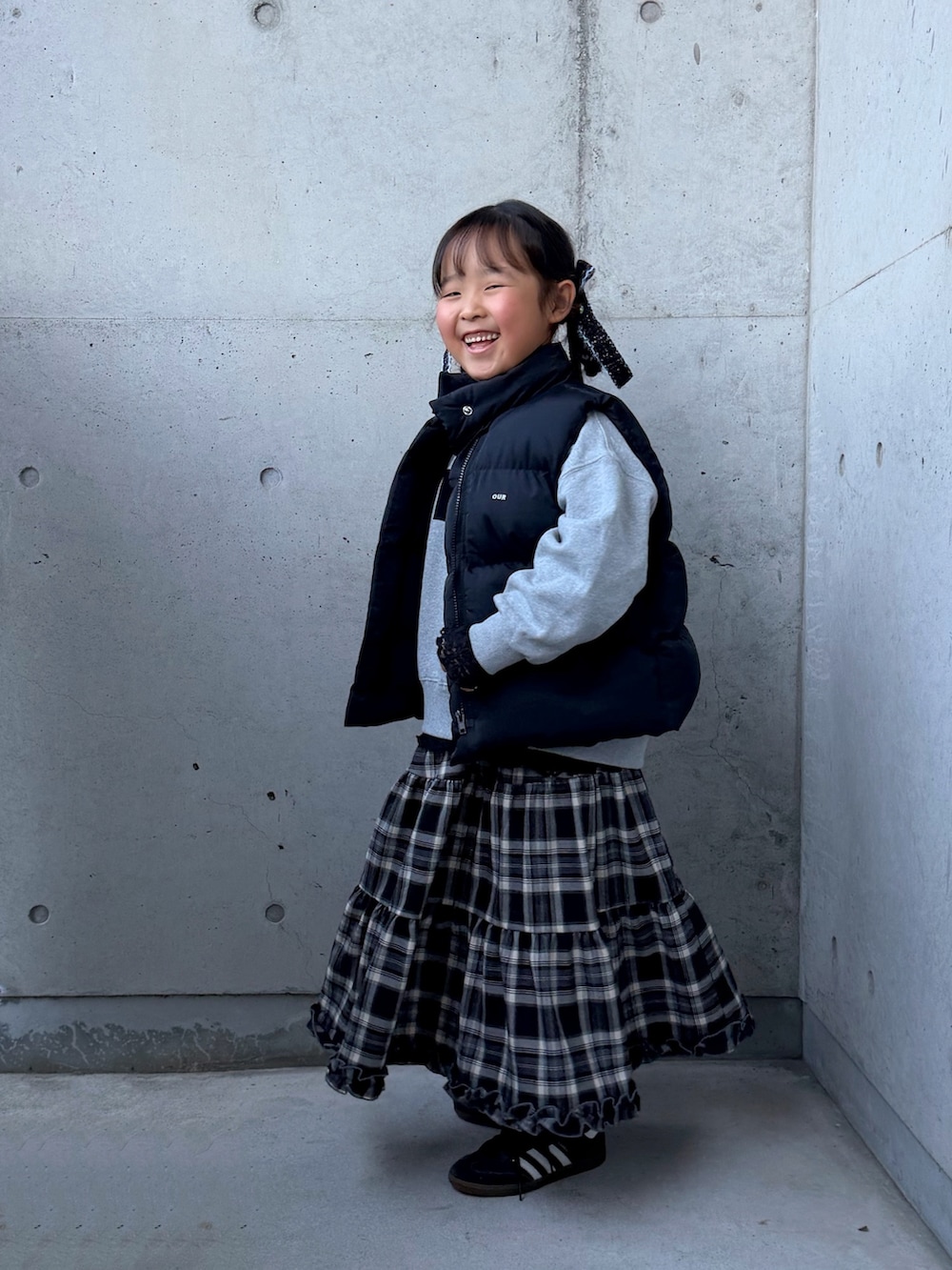 グレー系のスウェット、ブラック系のスニーカー、ブラウン系のスカートを着用したキッズの秋コーディネートの3枚目の写真