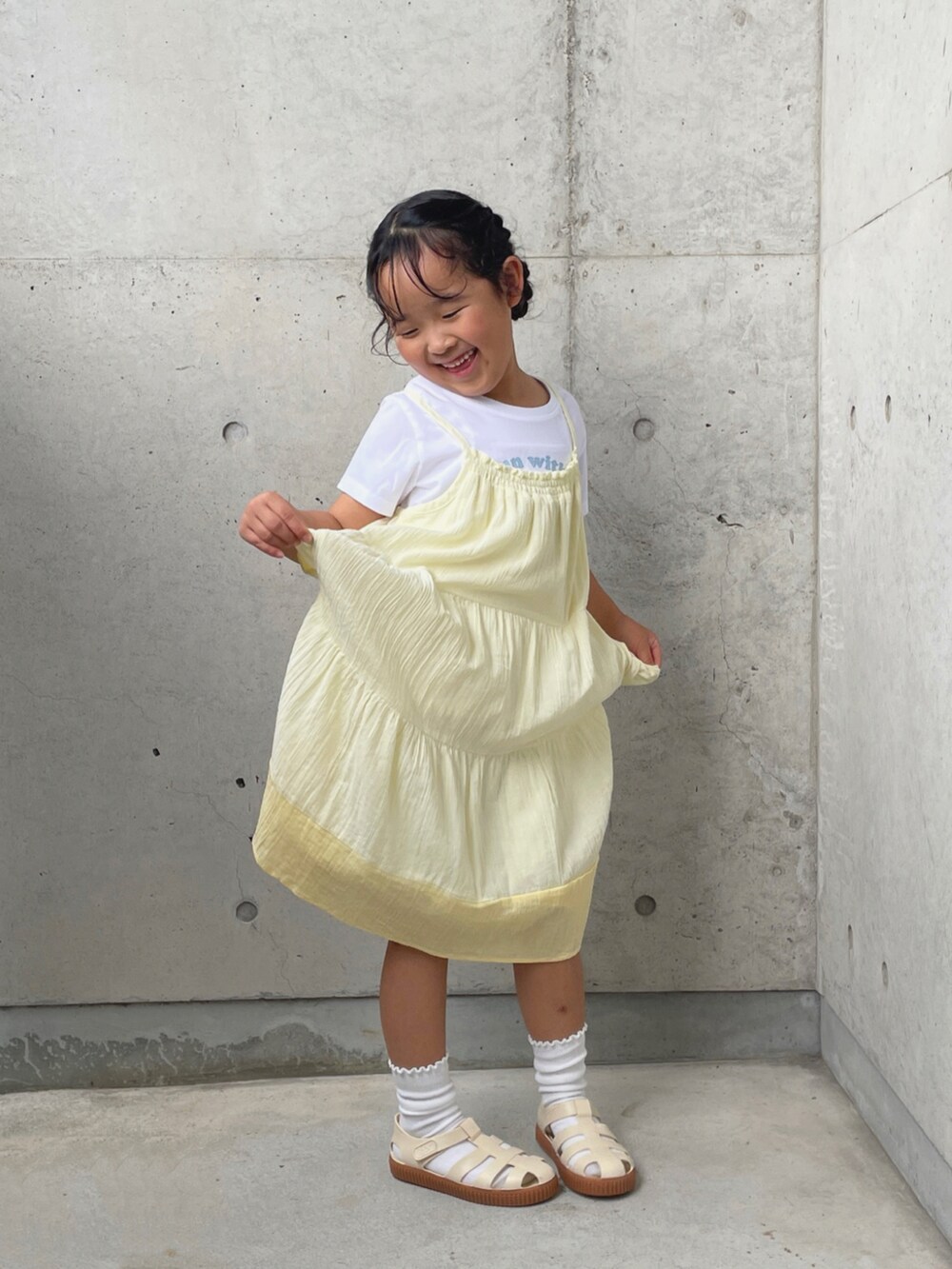 ホワイト系のサンダル、ホワイト系のTシャツ/カットソー、イエロー系のワンピースを着用したキッズの夏コーディネートの2枚目の写真