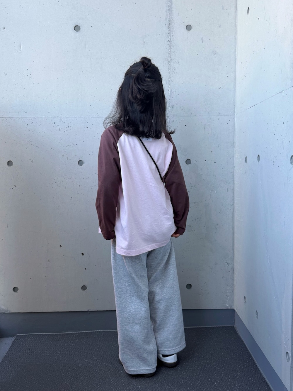 ピンク系のTシャツ/カットソー、ブラウン系のショルダーバッグ、ホワイト系のスニーカーを着用したキッズの秋コーディネートの2枚目の写真