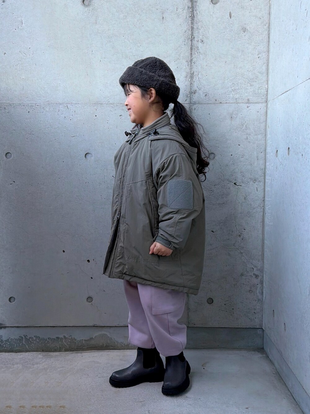 ピンク系のカーゴパンツ、グレー系のブーツ、グリーン系のブルゾンを着用したキッズの冬コーディネートの4枚目の写真
