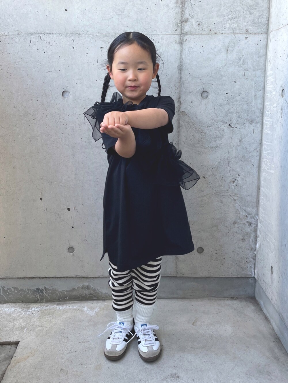 ブラック系のワンピース、ホワイト系のスニーカー、ブラック系のバレッタ/ヘアクリップを着用したキッズの春コーディネートの4枚目の写真