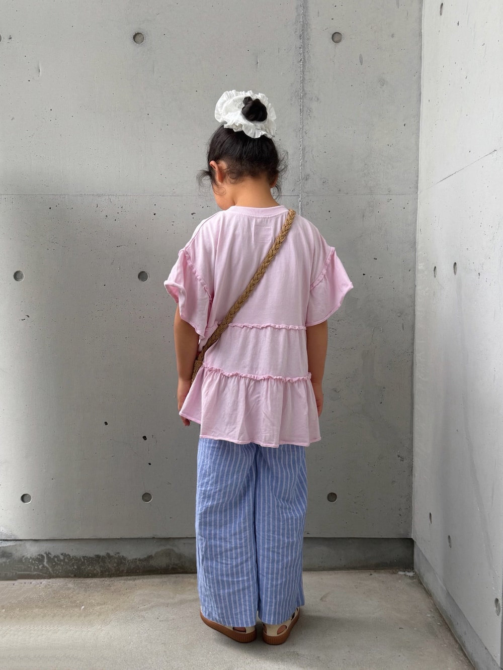 ピンク系のTシャツ/カットソー、ベージュ系のショルダーバッグ、ホワイト系のサンダルを着用したキッズの夏コーディネートの4枚目の写真