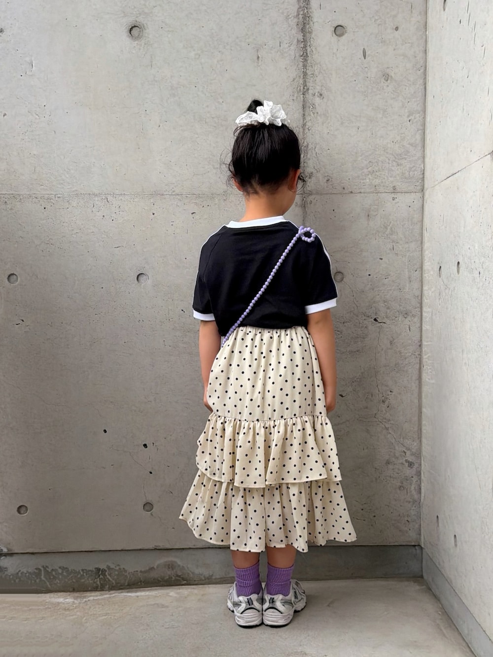 ホワイト系のスカート、ホワイト系のスニーカー、ブラック系のTシャツ/カットソーを着用したキッズの春コーディネートの4枚目の写真