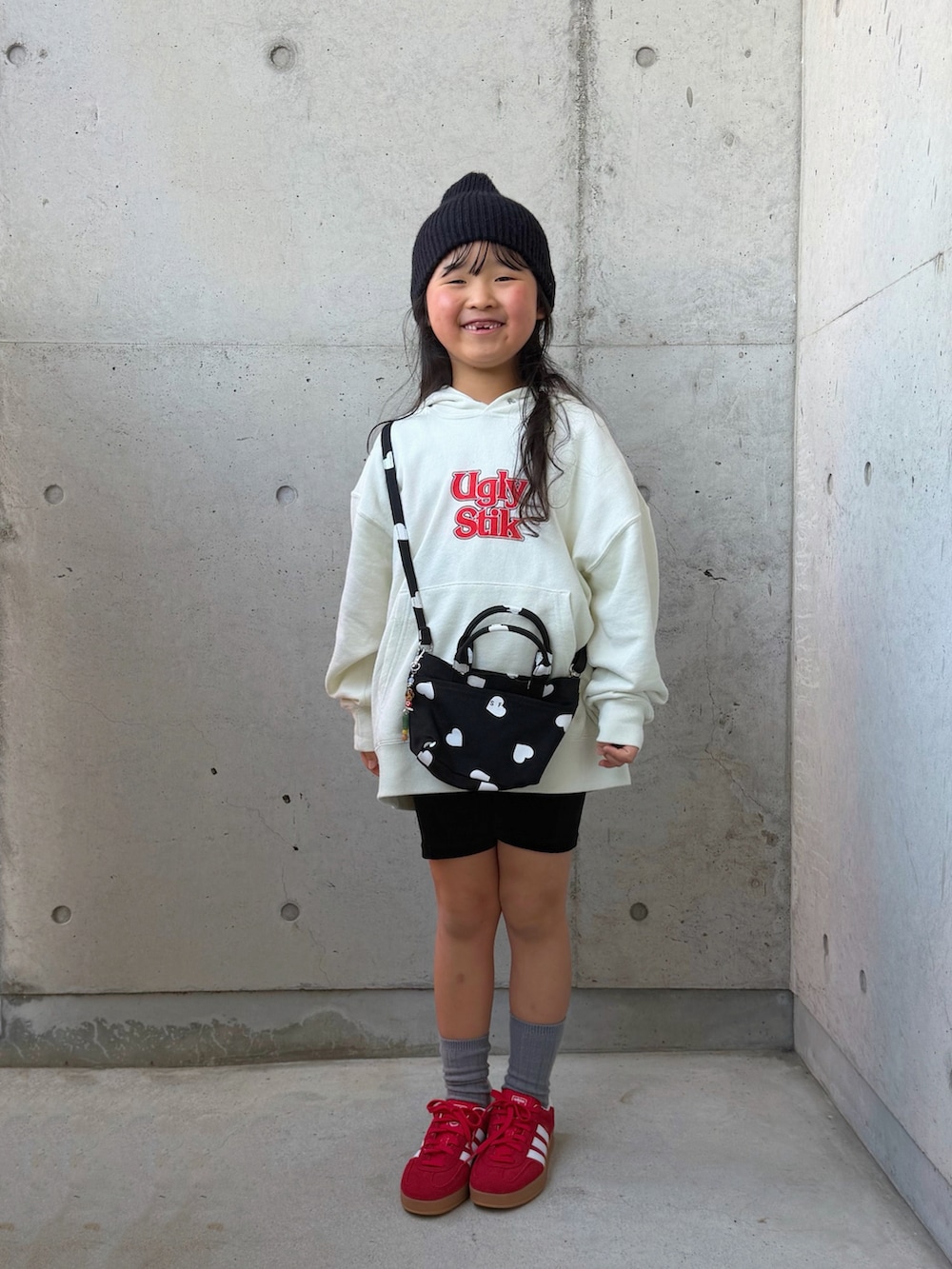ホワイト系のパーカー、ブラック系のショルダーバッグ、レッド系のスニーカーを着用したキッズの冬コーディネートの2枚目の写真