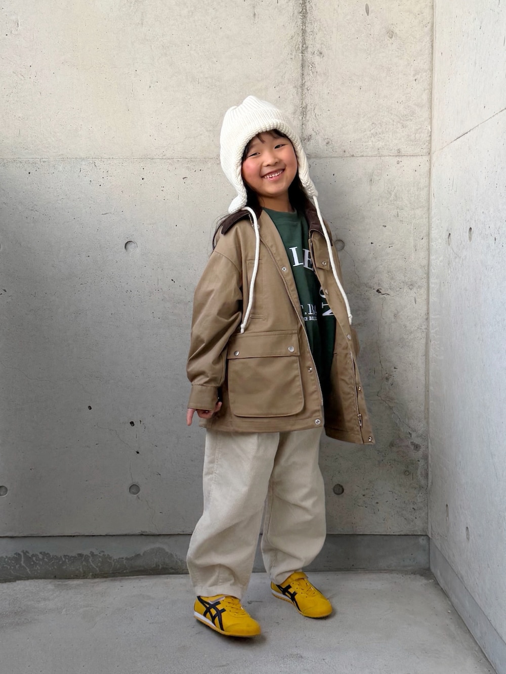 ベージュ系のミリタリージャケット、ベージュ系のその他パンツ、イエロー系のスニーカーを着用したキッズの秋コーディネートの2枚目の写真