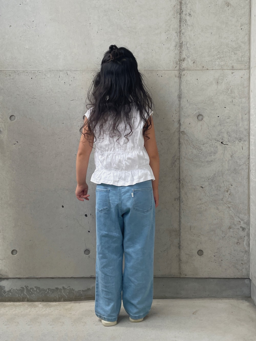 ホワイト系のサンダル、ブルー系のデニムパンツ、ホワイト系のトップスを着用したキッズの夏コーディネートの3枚目の写真