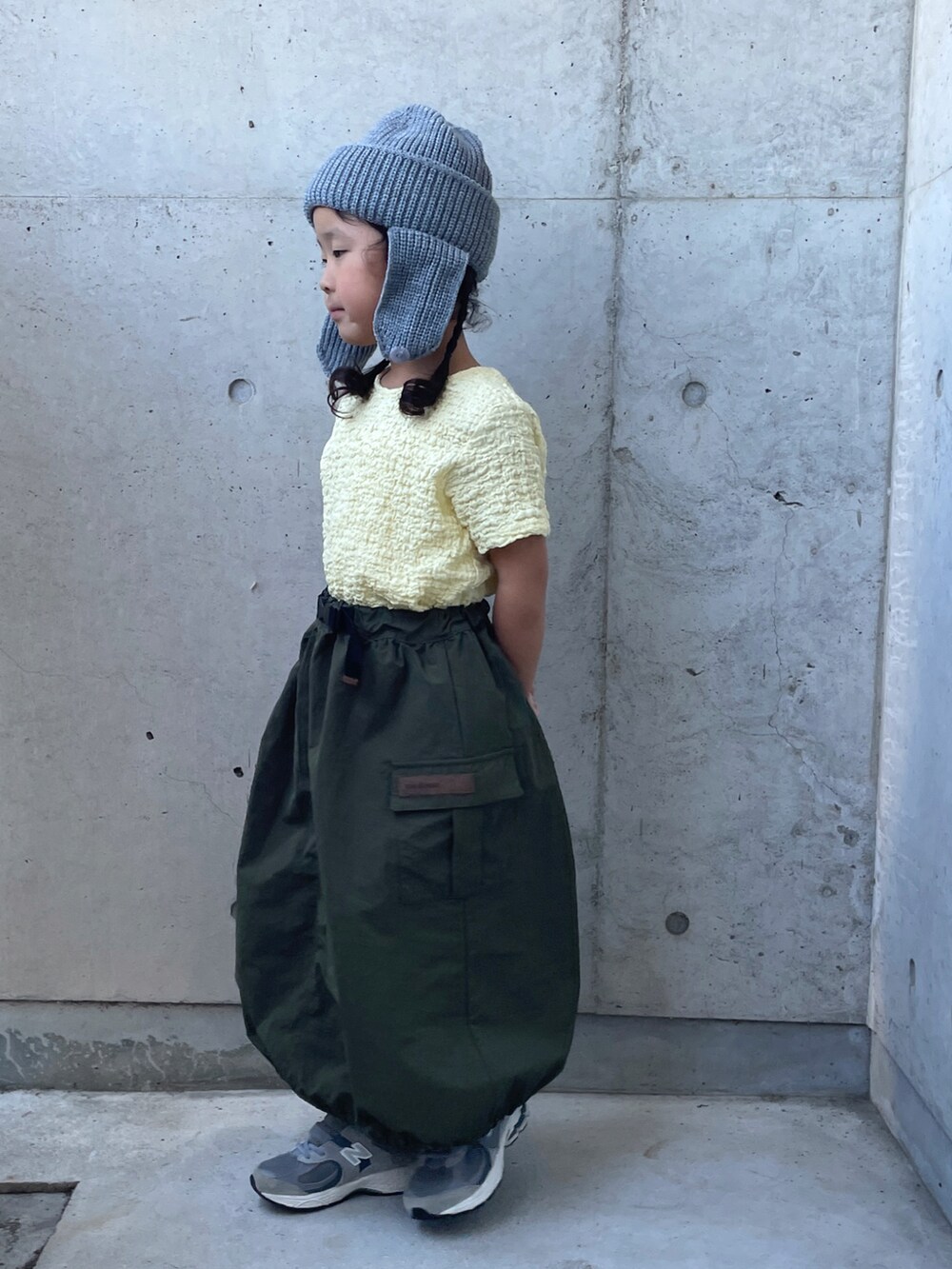 ベージュ系のTシャツ/カットソー、グレー系のスニーカー、グリーン系のスカートを着用したキッズの秋コーディネートの2枚目の写真