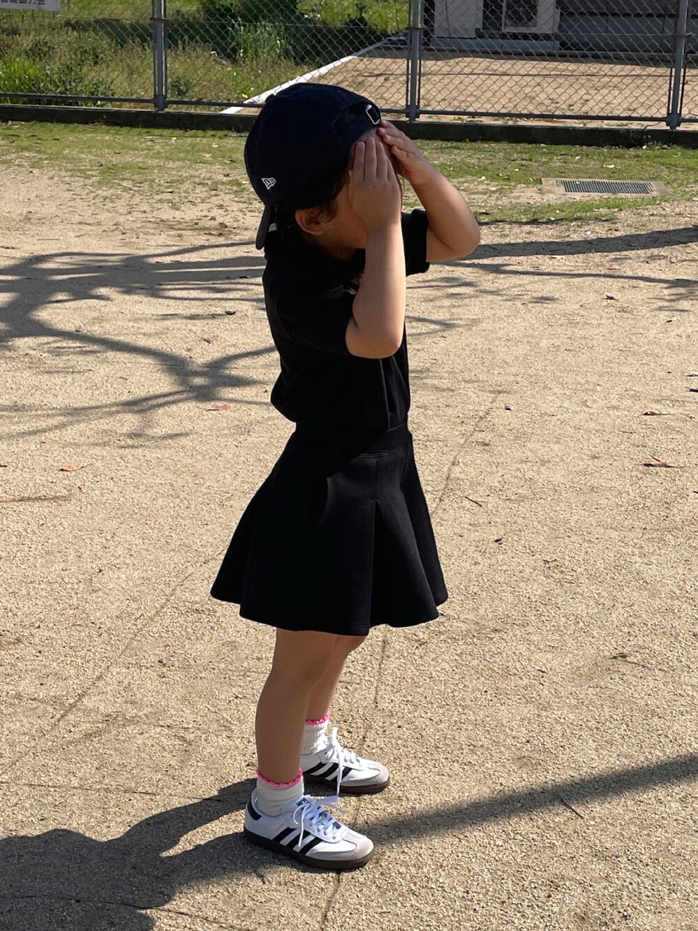 ブラック系のワンピース、ブラック系のスカート、ホワイト系のスニーカーを着用したキッズの春コーディネートの3枚目の写真