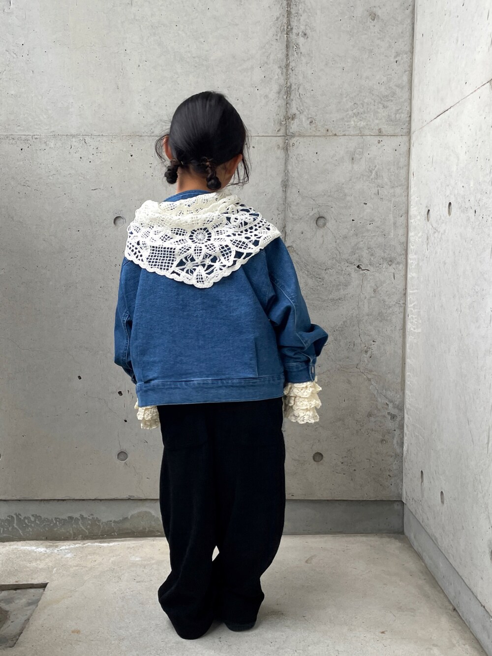 ブルー系のデニムジャケット、ブラック系のサロペット/オーバーオール、ブラック系のスニーカーを着用したキッズの春コーディネートの3枚目の写真