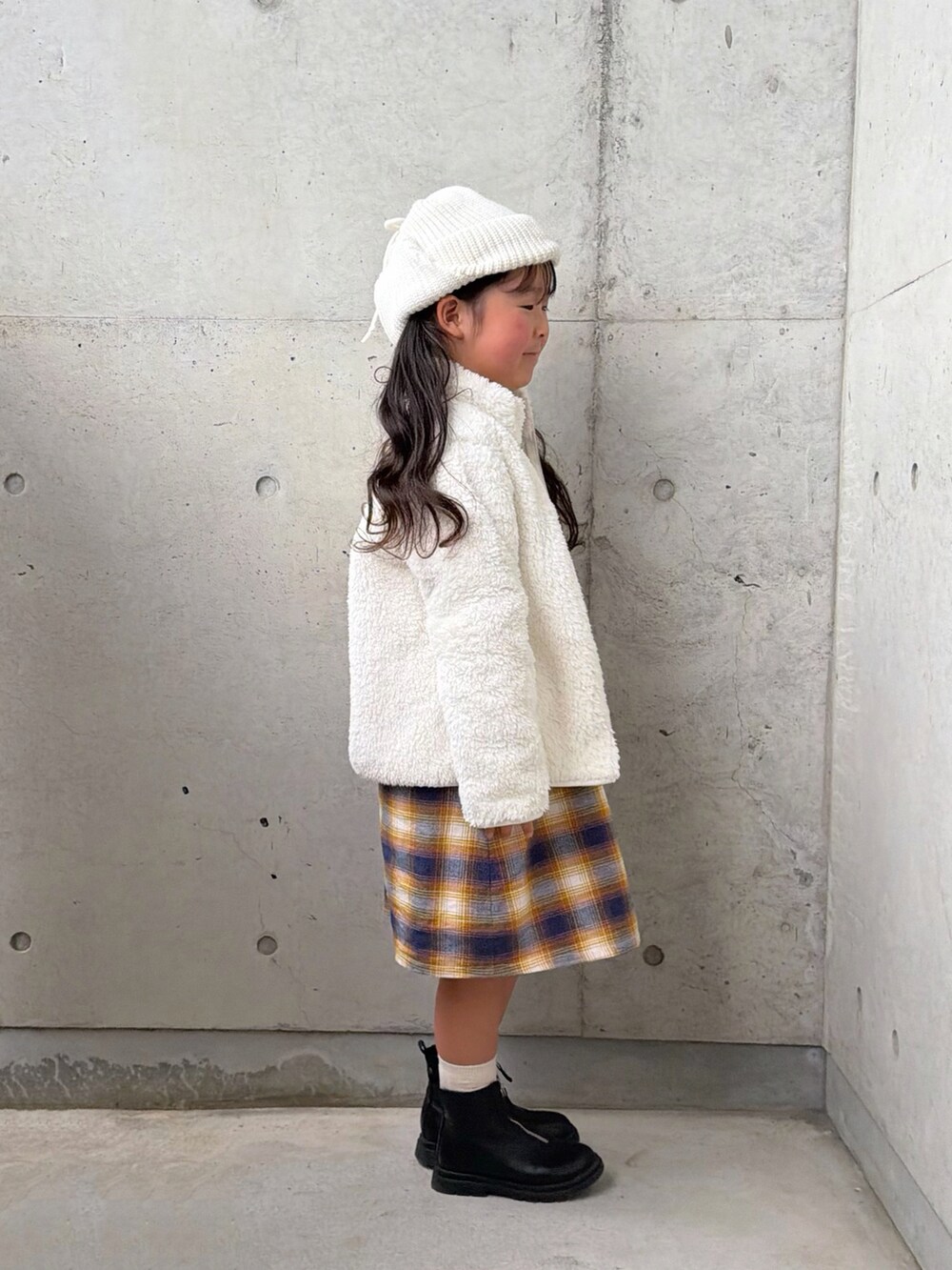 ブラック系のブーツ、ホワイト系のジャケット/アウター、イエロー系のワンピースを着用したキッズの秋コーディネートの4枚目の写真