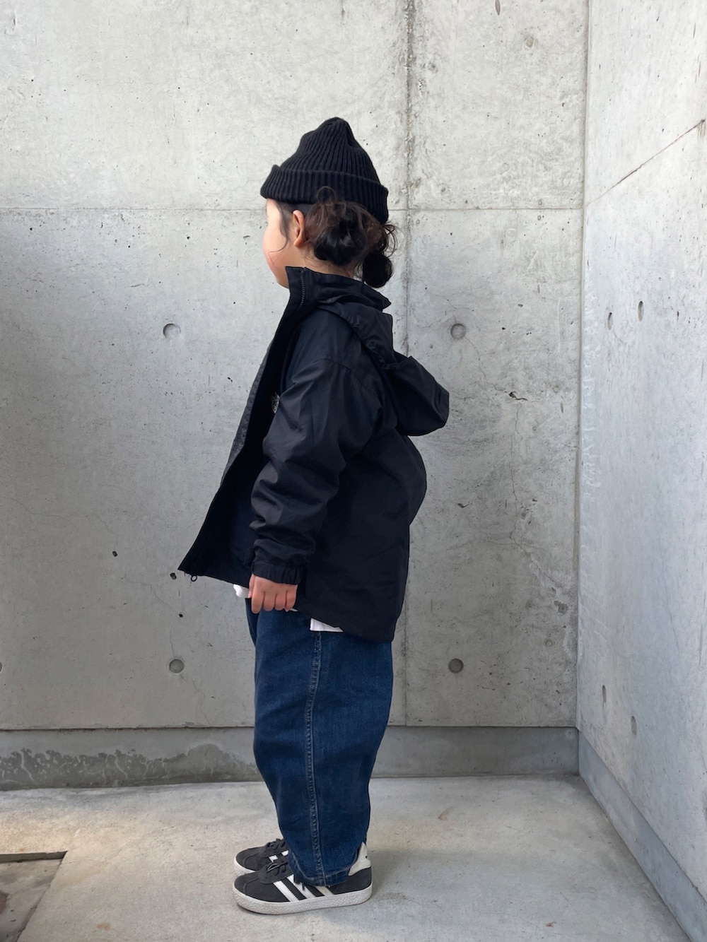 ブラック系のナイロンジャケット、グレー系のスウェット、ブルー系のデニムパンツを着用したキッズの冬コーディネートの4枚目の写真