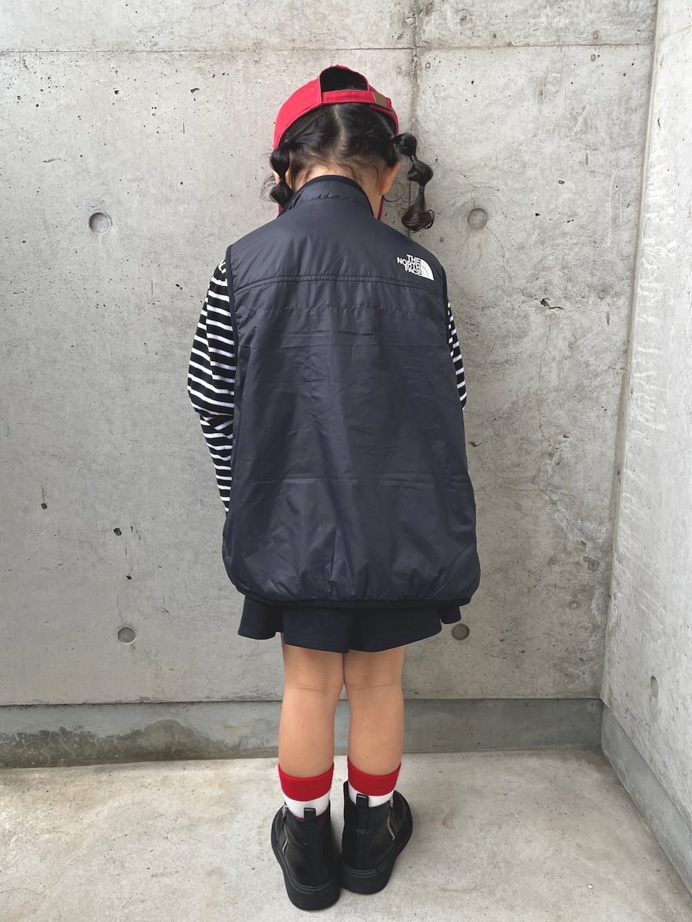 ブラック系のベスト、グレー系のワンピース、ブラック系のブーツを着用したキッズの春コーディネートの3枚目の写真