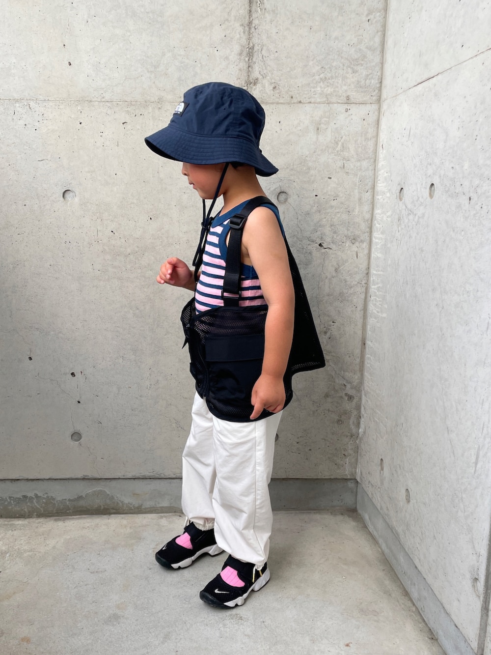 ブルー系のタンクトップ、ブラック系のベスト、ホワイト系のカーゴパンツを着用したキッズの春コーディネートの2枚目の写真