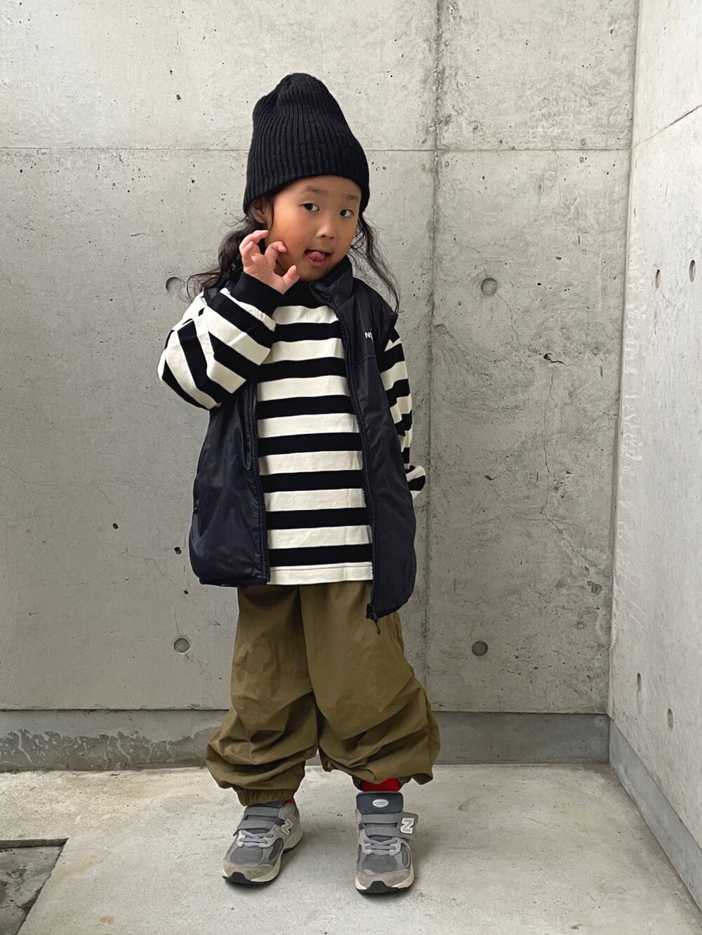 ブラック系のベスト、ブラック系のTシャツ/カットソー、グリーン系のパンツを着用したキッズの秋コーディネートの2枚目の写真