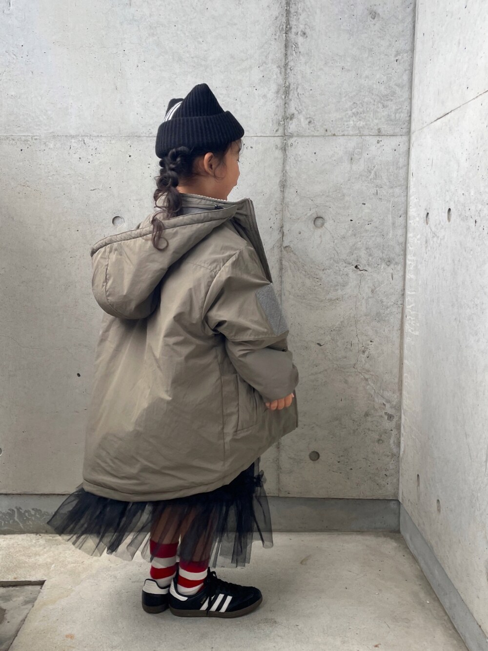 グリーン系のブルゾン、ブラック系のスカート、ブラック系のスニーカーを着用したキッズの冬コーディネートの2枚目の写真