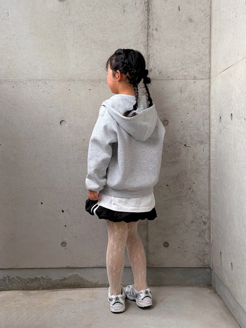 ホワイト系のTシャツ/カットソー、ブラック系のスカート、ホワイト系のスニーカーを着用したキッズの冬コーディネートの2枚目の写真