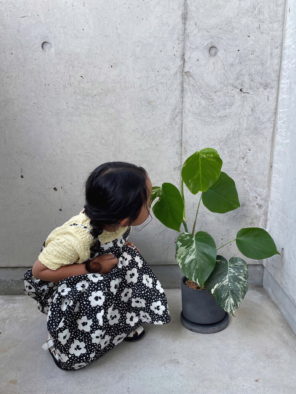 ブラック系のワンピース、ホワイト系のサンダル、ベージュ系のTシャツ/カットソーを着用したキッズの春コーディネートの5枚目の写真