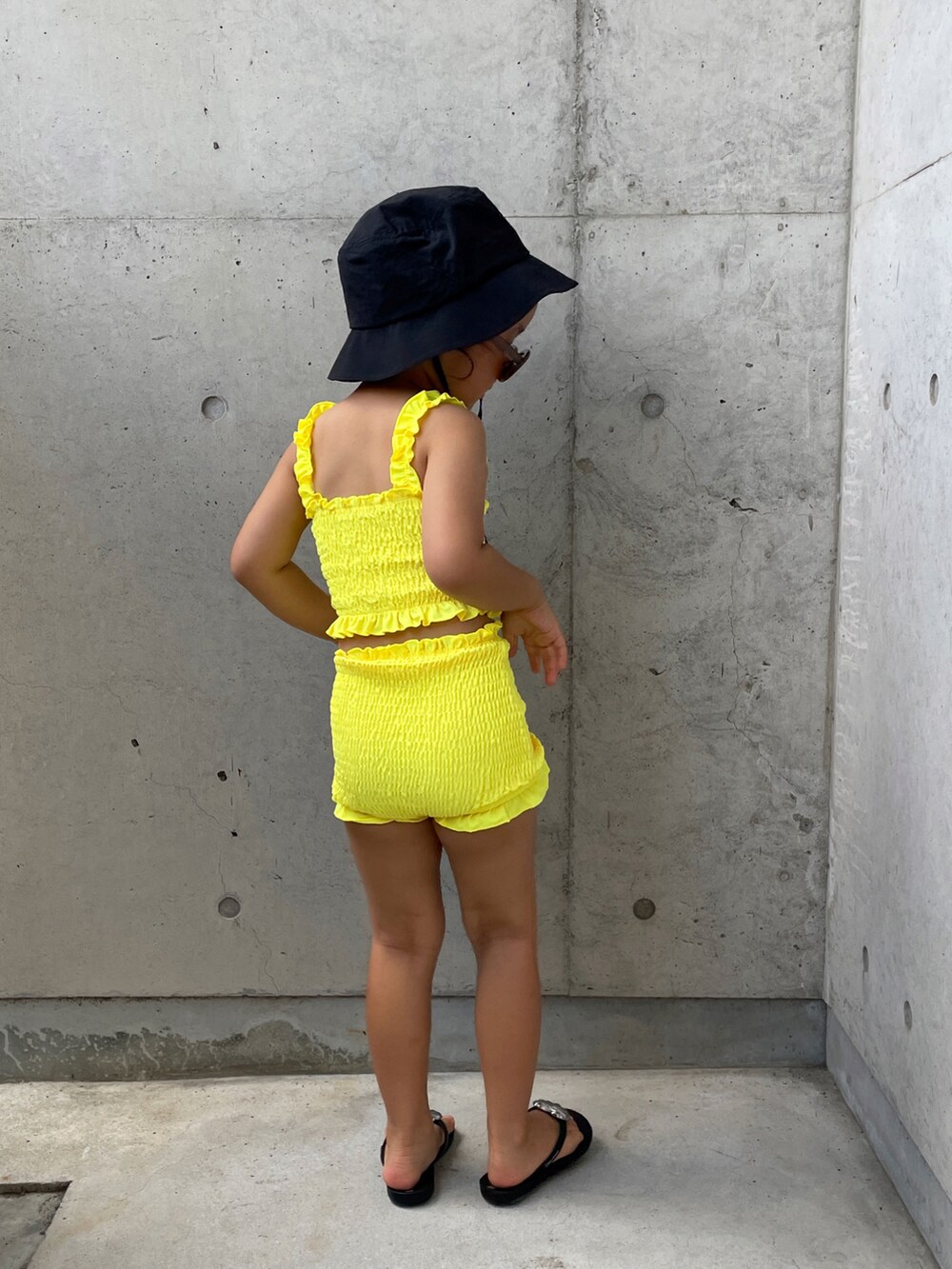 ブラック系のサンダル、イエロー系の水着、ブラック系のハットを着用したキッズの夏コーディネートの4枚目の写真