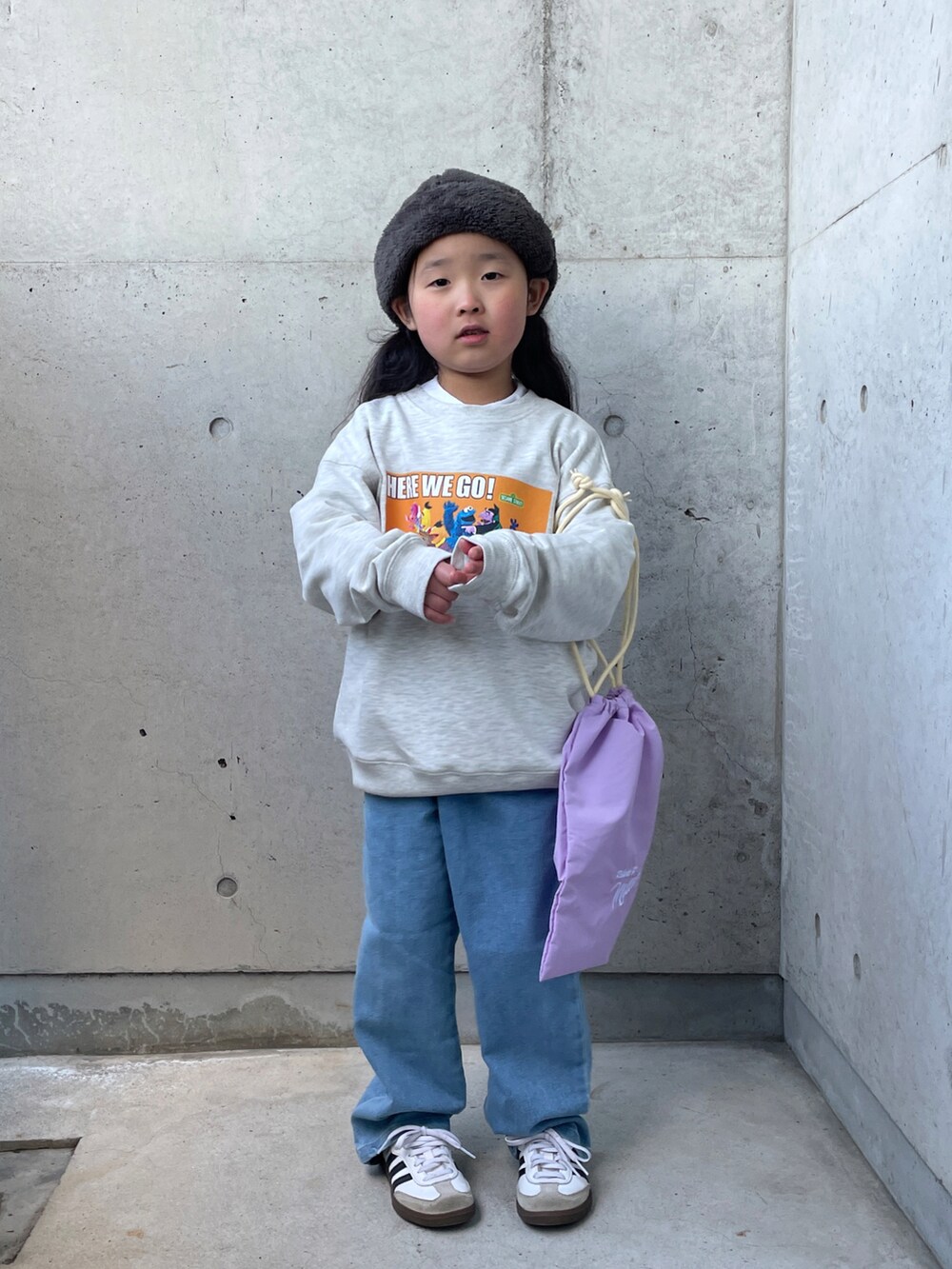 パープル系のエコバッグ/サブバッグ、グレー系のスウェット、ブルー系のデニムパンツを着用したキッズの冬コーディネートの2枚目の写真